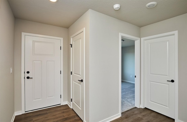 corridor featuring dark wood-style floors, a textured ceiling, and baseboards