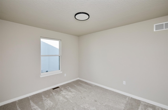 unfurnished room with visible vents, baseboards, a textured ceiling, and carpet flooring