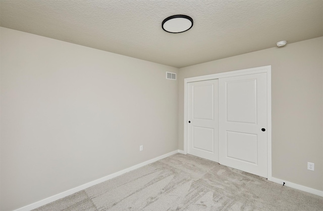 unfurnished bedroom with baseboards, visible vents, a closet, and light carpet