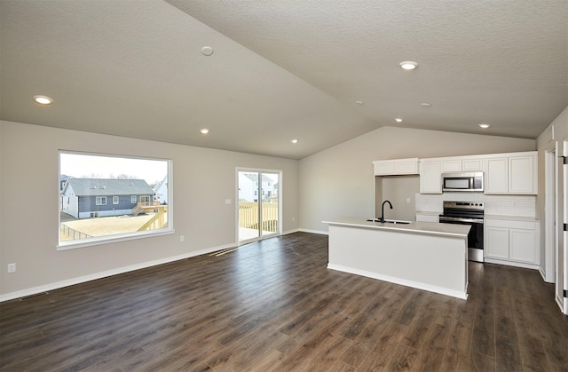 kitchen with an island with sink, open floor plan, dark wood finished floors, appliances with stainless steel finishes, and lofted ceiling