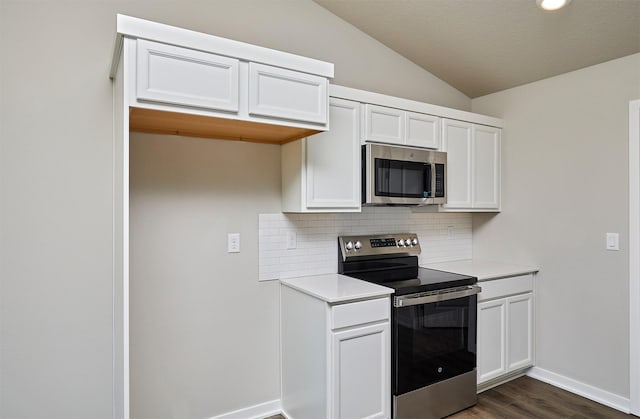 kitchen featuring dark wood-type flooring, light countertops, lofted ceiling, decorative backsplash, and stainless steel appliances