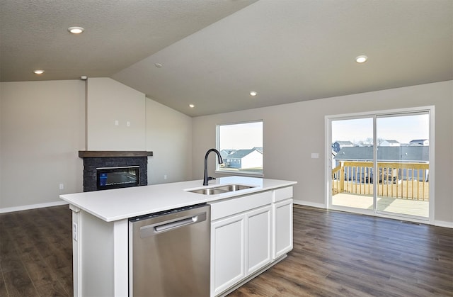 kitchen with a glass covered fireplace, lofted ceiling, a kitchen island with sink, a sink, and dishwasher