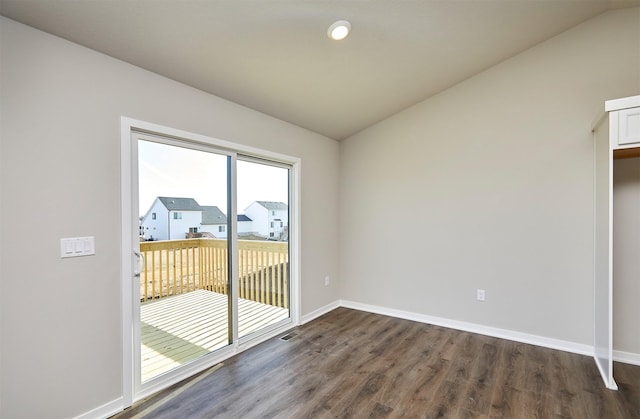 spare room featuring visible vents, baseboards, dark wood-style floors, and vaulted ceiling