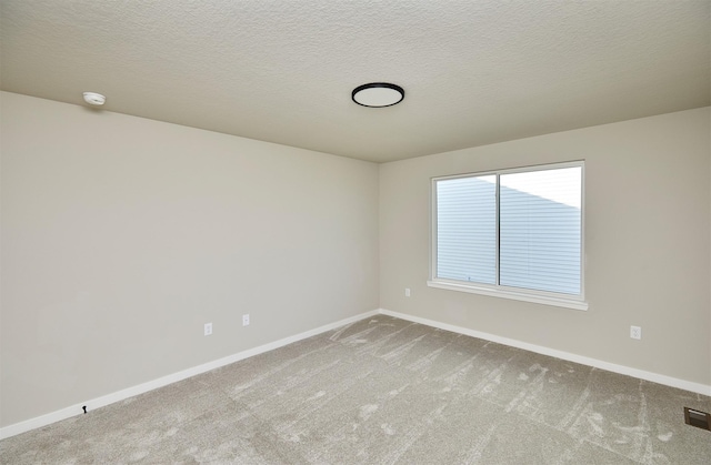 carpeted spare room with visible vents, a textured ceiling, and baseboards