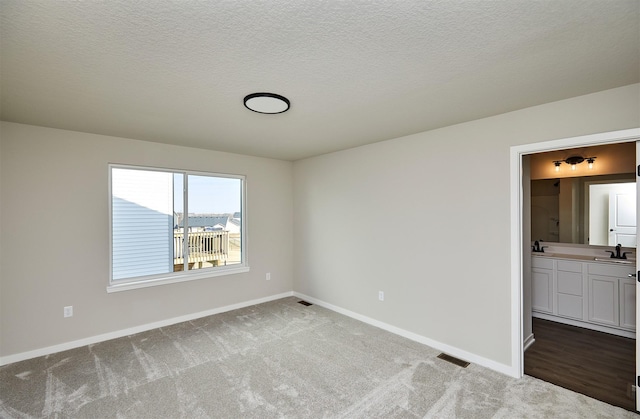 unfurnished room with baseboards, carpet, visible vents, and a sink