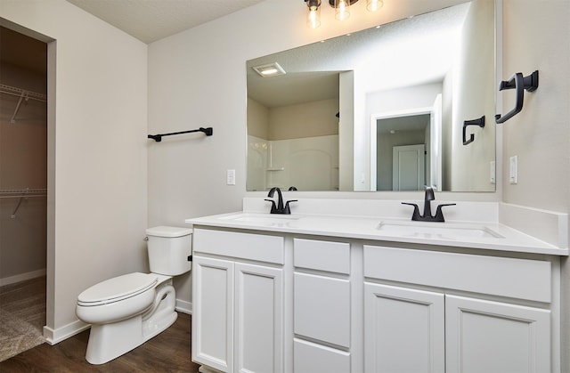 full bathroom with double vanity, toilet, wood finished floors, and a sink