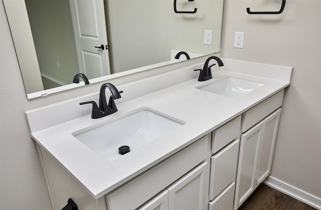 full bath featuring double vanity, baseboards, and a sink