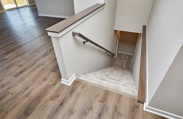 staircase with baseboards and wood finished floors