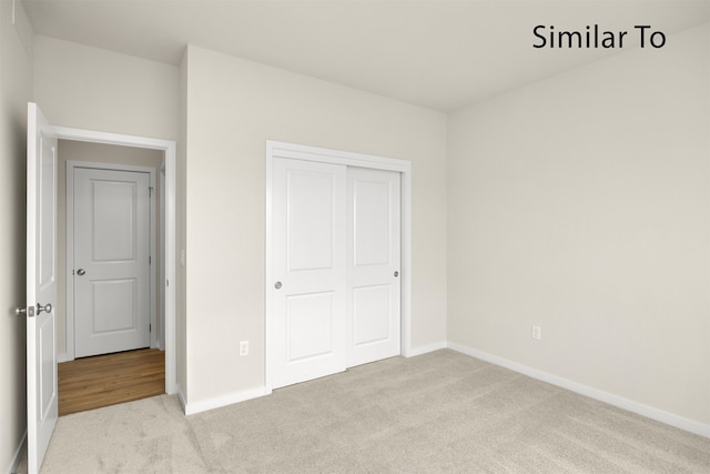 unfurnished bedroom featuring light colored carpet and a closet