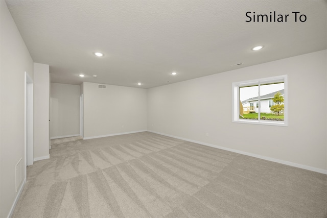 empty room featuring light carpet and a textured ceiling