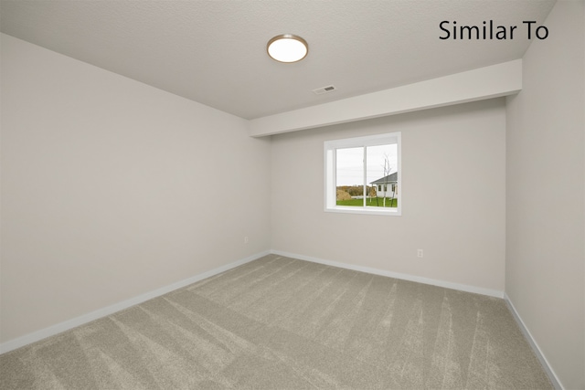 carpeted empty room with a textured ceiling