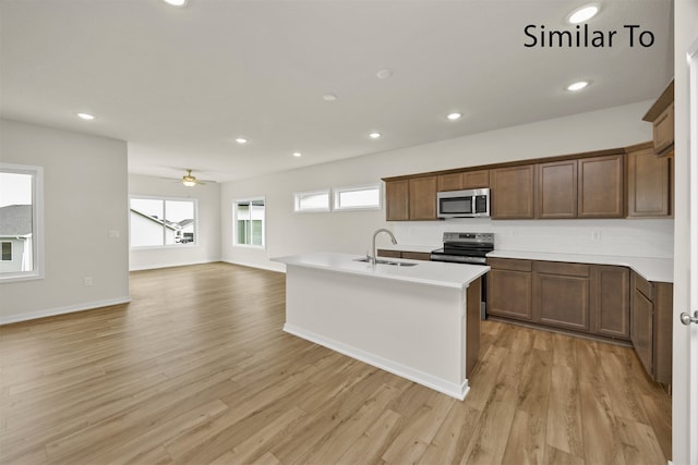 kitchen with appliances with stainless steel finishes, light wood-type flooring, ceiling fan, and sink