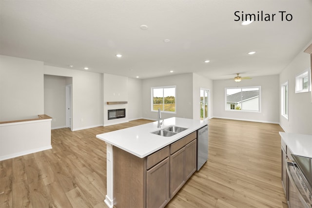 kitchen featuring ceiling fan, sink, light hardwood / wood-style flooring, a center island with sink, and appliances with stainless steel finishes