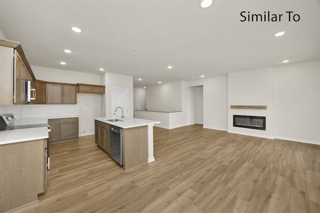 kitchen with appliances with stainless steel finishes, light wood-type flooring, a center island with sink, and sink