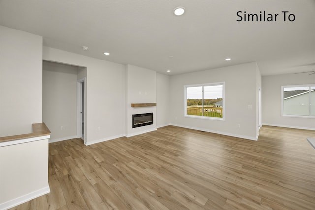 unfurnished living room with ceiling fan and light wood-type flooring