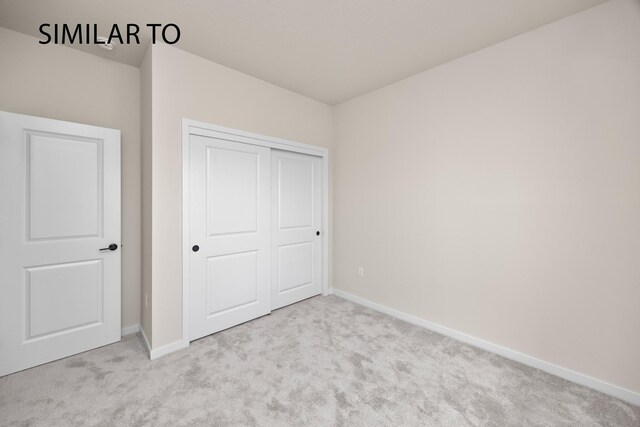 unfurnished bedroom featuring light colored carpet and a closet