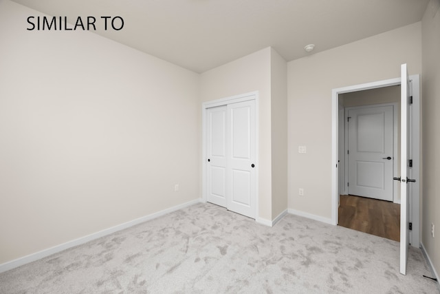 unfurnished bedroom featuring light colored carpet and a closet