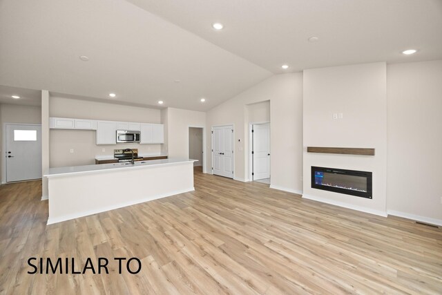 unfurnished living room with light hardwood / wood-style flooring, lofted ceiling, and sink