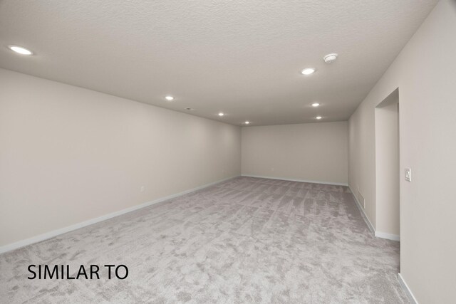 spare room featuring a textured ceiling and light colored carpet