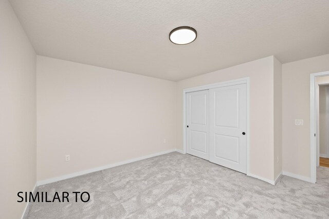 unfurnished bedroom with light carpet, a closet, and a textured ceiling