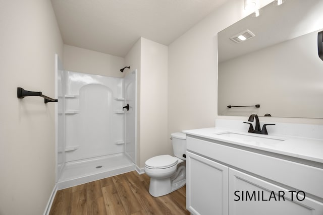 bathroom featuring toilet, a shower, wood-type flooring, and vanity