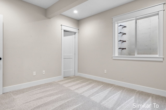 carpeted spare room with beamed ceiling