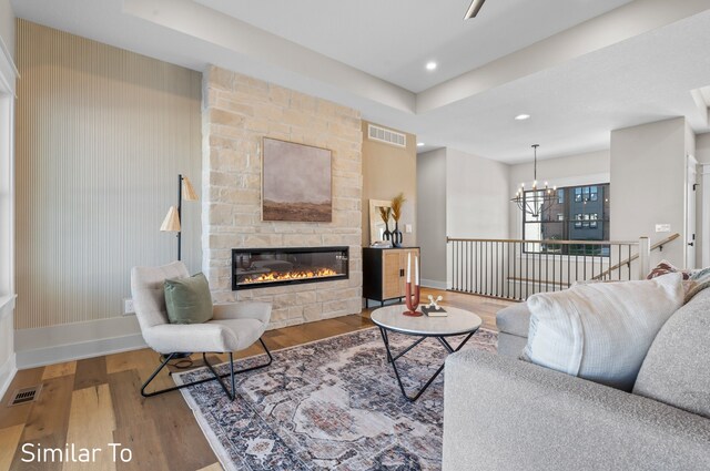 living room with a fireplace, a notable chandelier, and hardwood / wood-style flooring