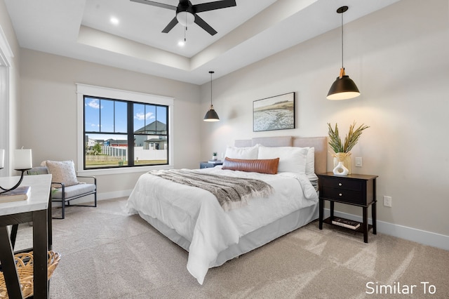 bedroom with light colored carpet, ceiling fan, and a tray ceiling