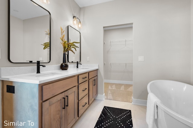 bathroom with a washtub, vanity, and tile patterned flooring