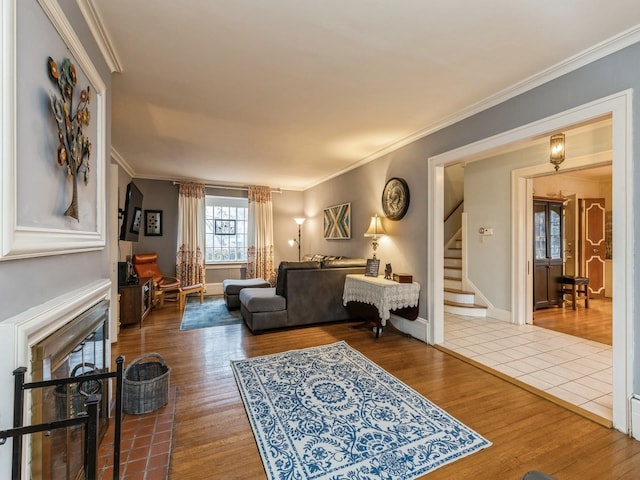 living room featuring hardwood / wood-style flooring, ornamental molding, and a brick fireplace