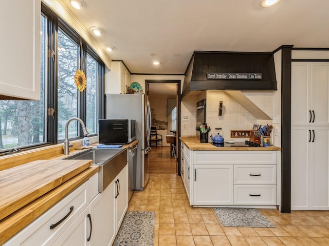 kitchen featuring white cabinets, plenty of natural light, wood counters, and sink