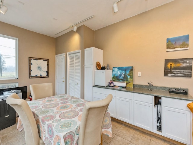 dining area featuring rail lighting and light tile patterned flooring