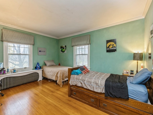 bedroom with light wood-type flooring, radiator, and ornamental molding