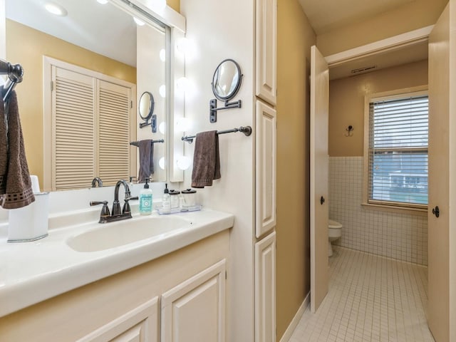 bathroom with tile patterned floors, vanity, tile walls, and toilet