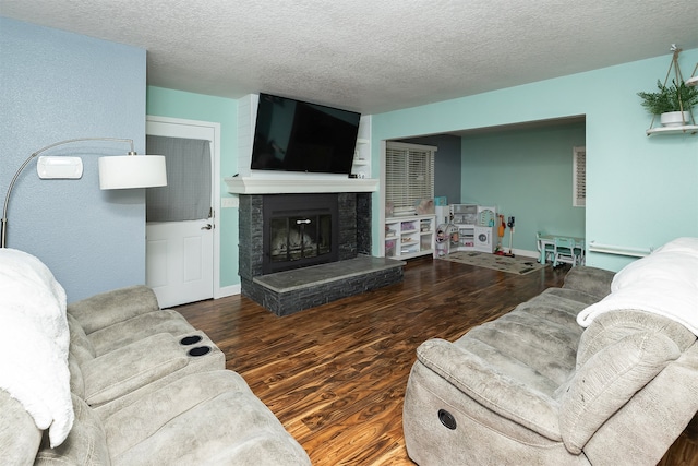 living room with dark hardwood / wood-style floors, a brick fireplace, and a textured ceiling