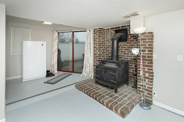 living room featuring concrete floors, a textured ceiling, and a wood stove