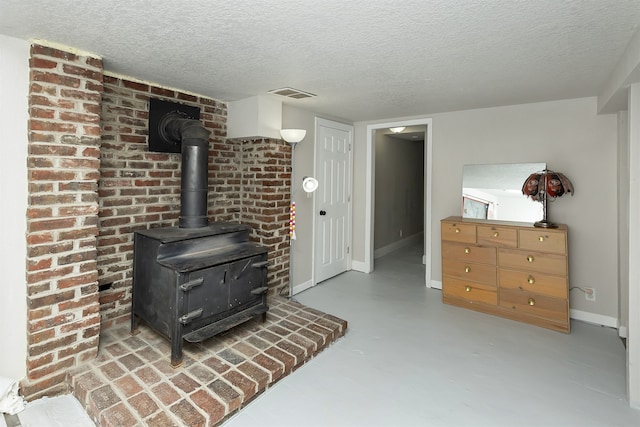 interior space with a wood stove and a textured ceiling