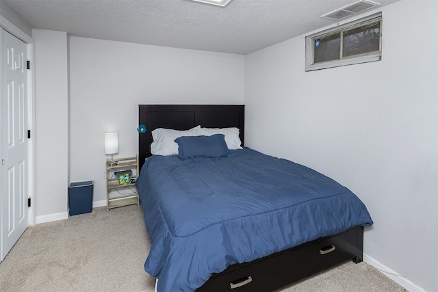 bedroom with light colored carpet and a textured ceiling