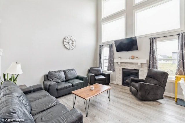 living room featuring plenty of natural light, light hardwood / wood-style floors, and a towering ceiling