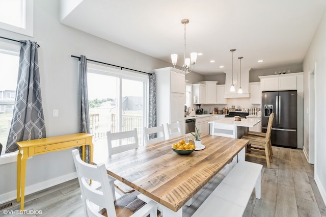 dining room with sink, light hardwood / wood-style floors, and an inviting chandelier