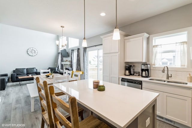 kitchen with white cabinetry, sink, backsplash, a kitchen island, and light wood-type flooring