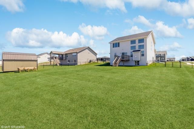 back of house featuring stairs, a lawn, an outbuilding, and a fenced backyard