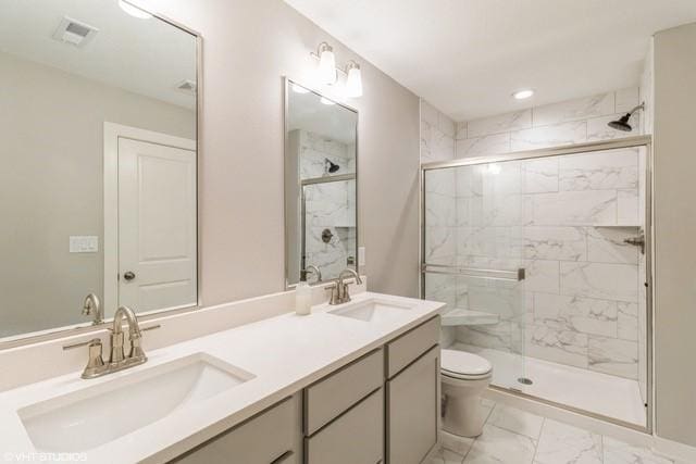 full bathroom with marble finish floor, a sink, a shower stall, and toilet