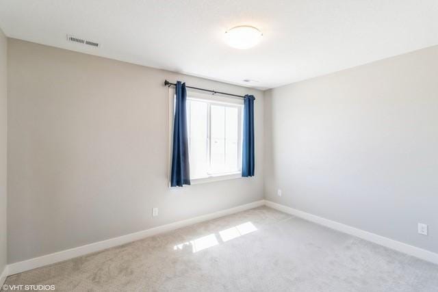 carpeted empty room with baseboards and visible vents