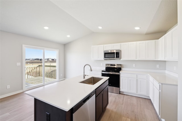 kitchen featuring sink, stainless steel appliances, an island with sink, white cabinets, and vaulted ceiling