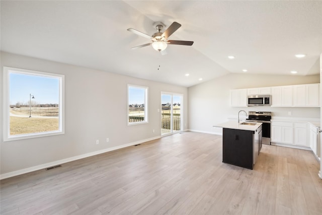 kitchen with lofted ceiling, light hardwood / wood-style flooring, an island with sink, stainless steel appliances, and white cabinets