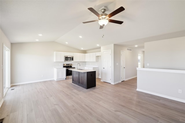 kitchen featuring lofted ceiling, sink, white cabinetry, stainless steel appliances, and an island with sink