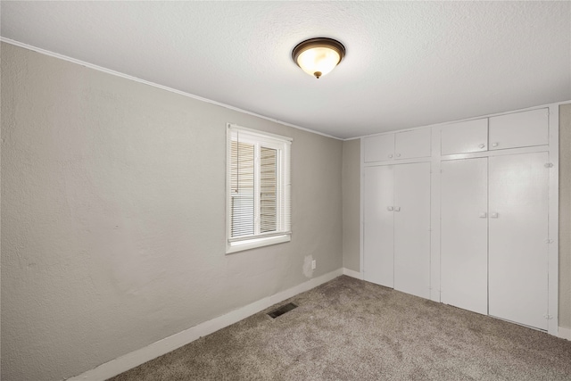 unfurnished bedroom featuring a textured ceiling, light colored carpet, a closet, and crown molding