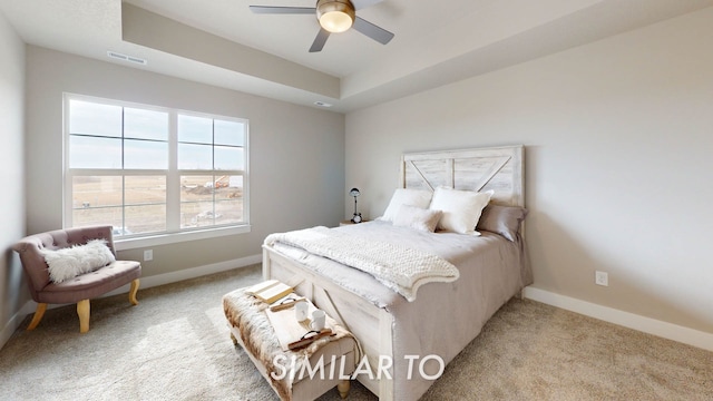 carpeted bedroom featuring a raised ceiling and ceiling fan