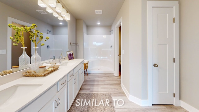 bathroom featuring walk in shower, wood-type flooring, and vanity